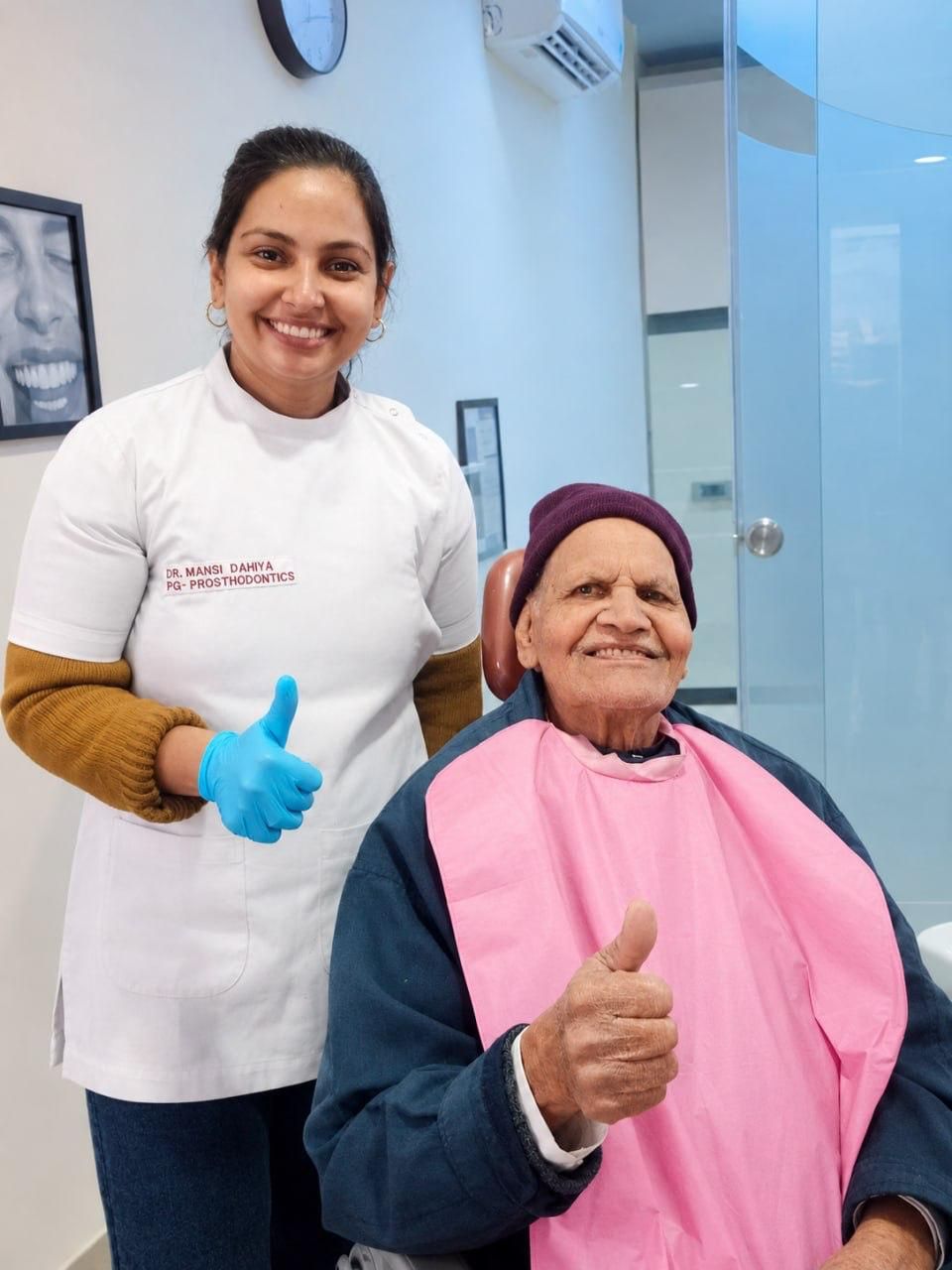 An elderly patient giving a thumbs up with Dr. Mansi Dahiya Malik after treatment