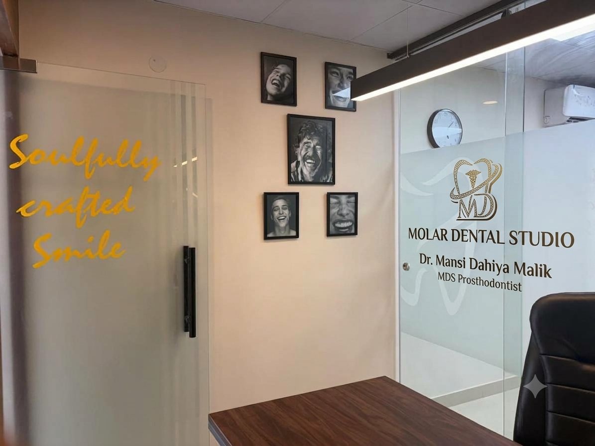 The inner door at Molar Dental Studio, Soulfully crafted Smile lettered in gold beside framed black-and-white portraits, with the studio monogram etched on the glass partition